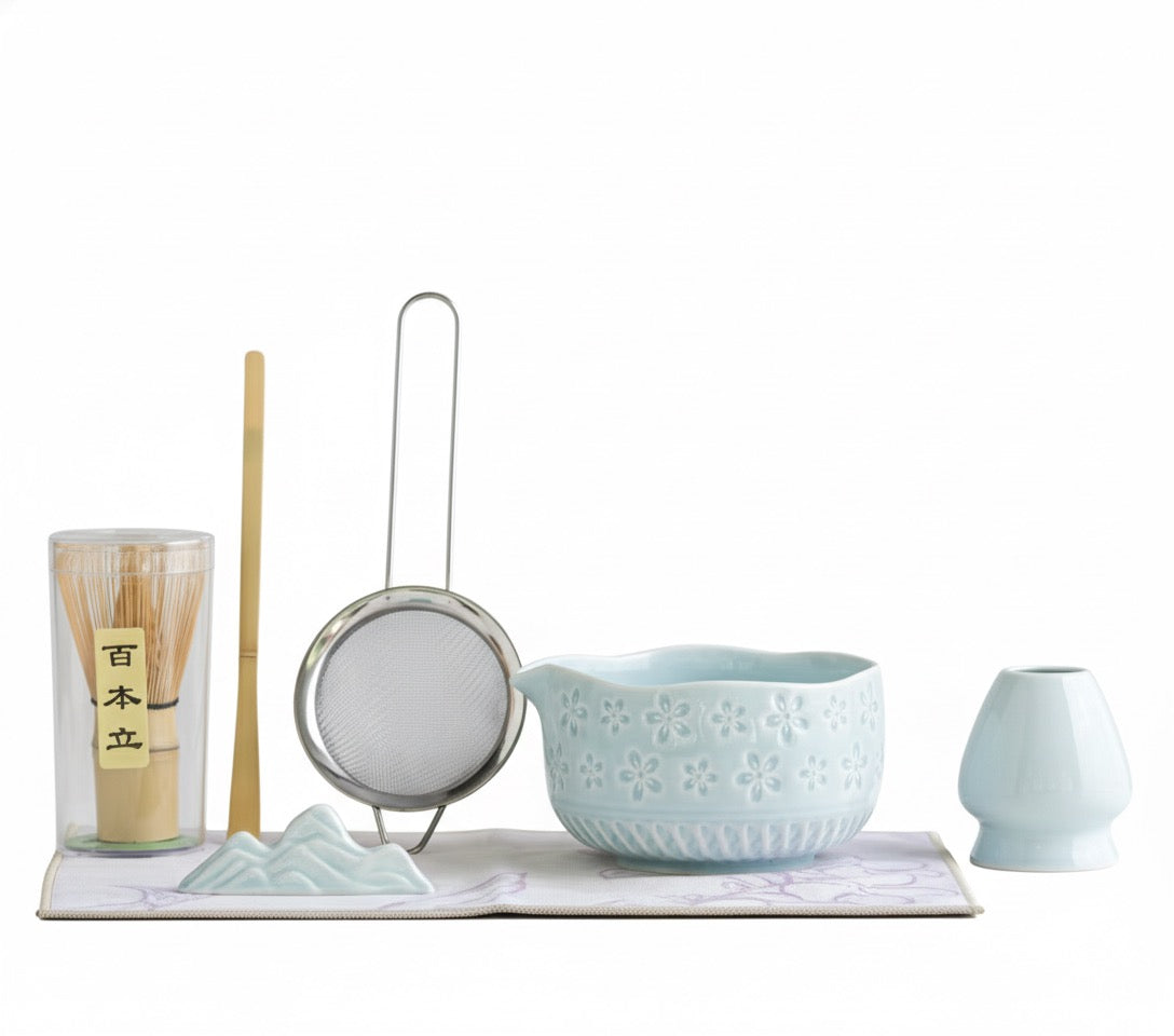 Tea-making set with ceramic bowl, strainer, and other tools on a white background
