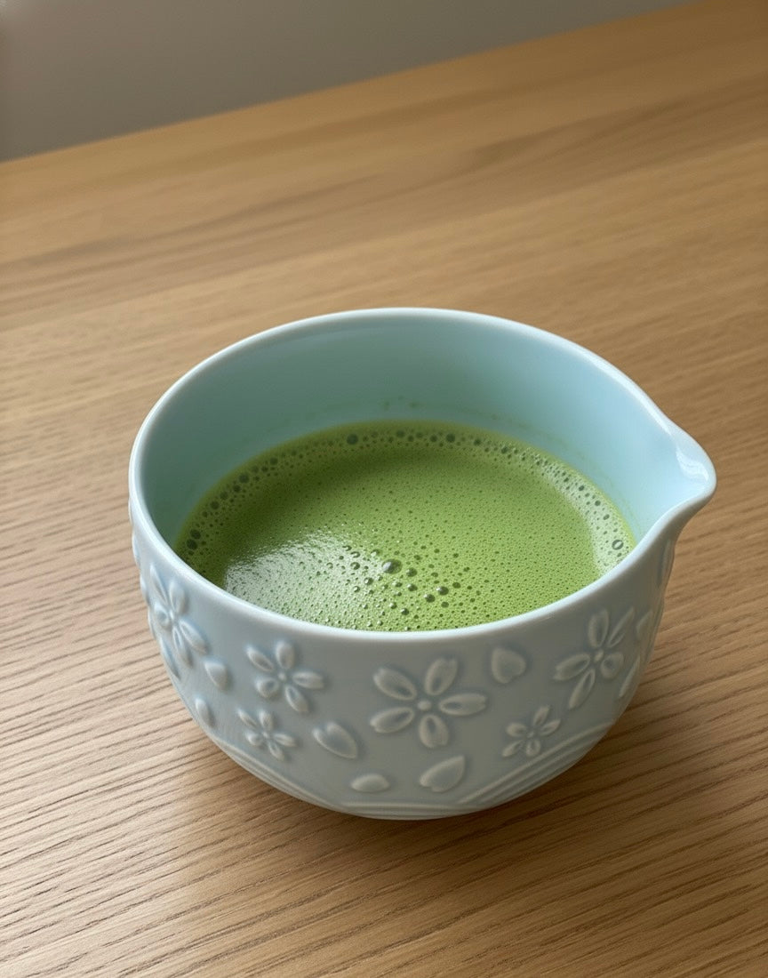 Ceramic bowl with green tea on a wooden surface