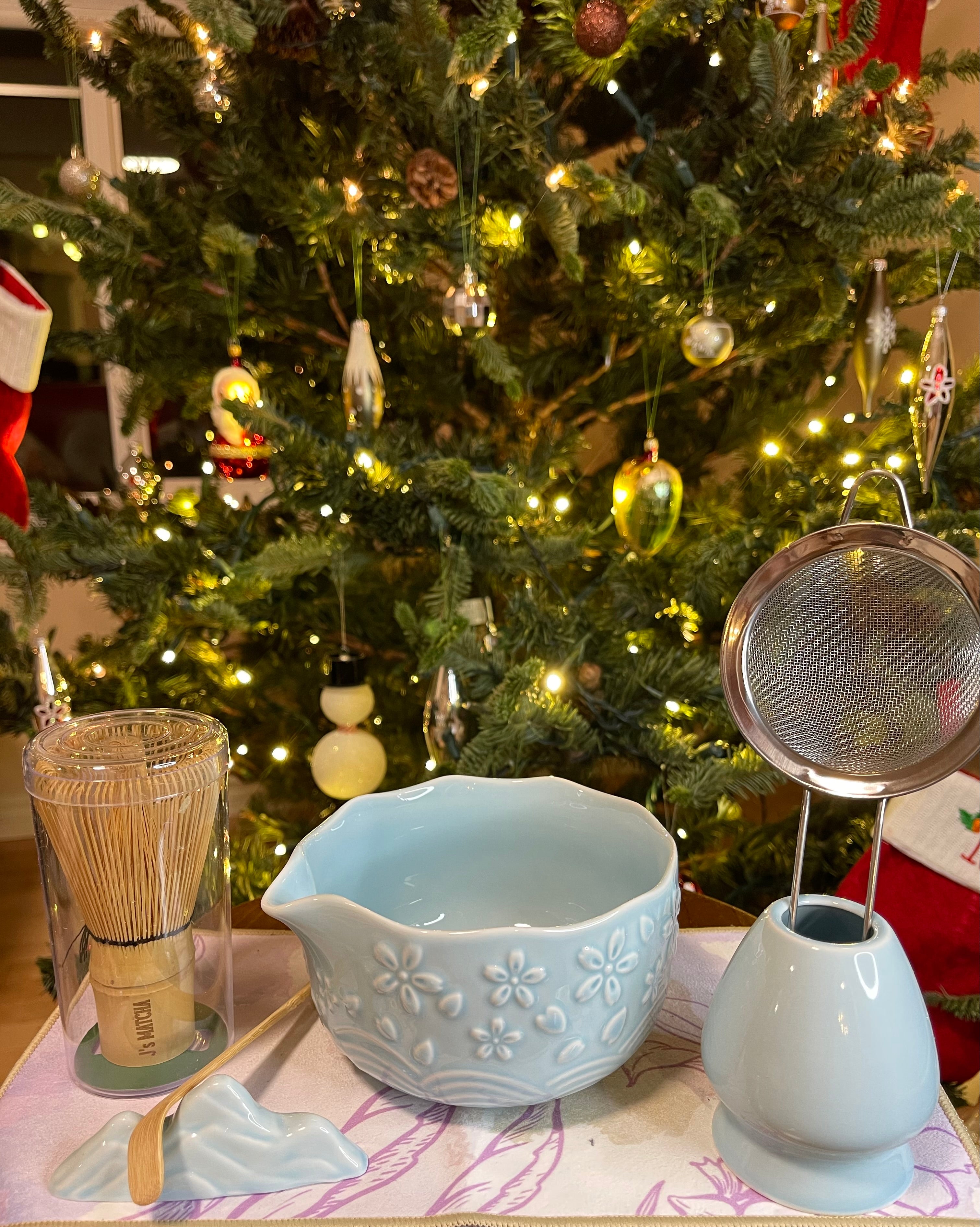 Tea-making accessories on a table with a decorated Christmas tree in the background
