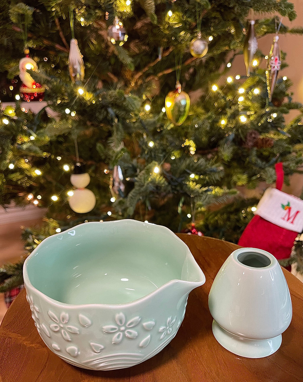Decorative ceramic bowl and salt shaker on a table with a Christmas tree in the background