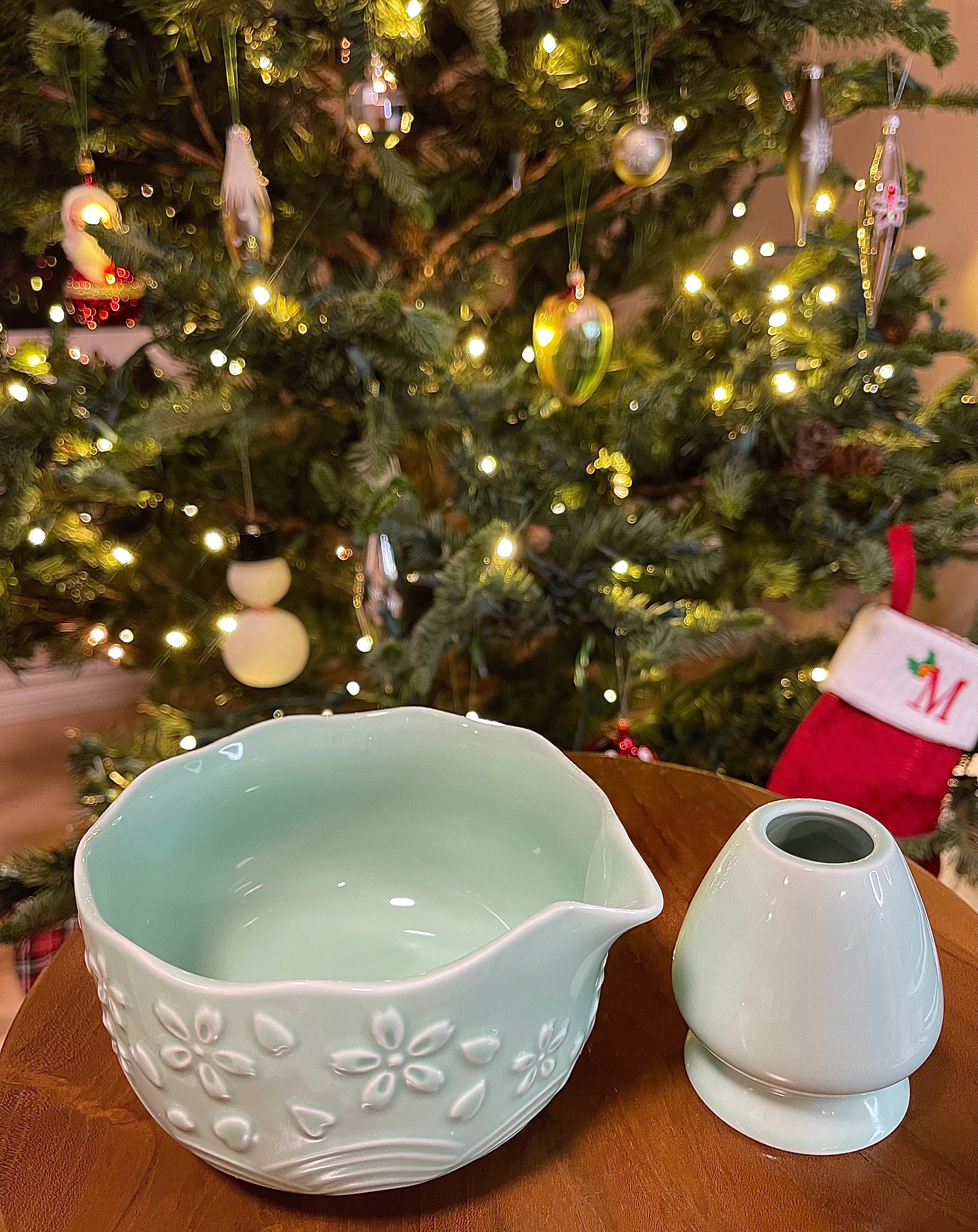 Decorative ceramic bowl and salt shaker on a table with a Christmas tree in the background