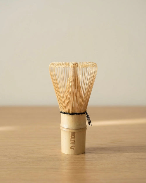 Bamboo whisk on a wooden surface with a neutral background